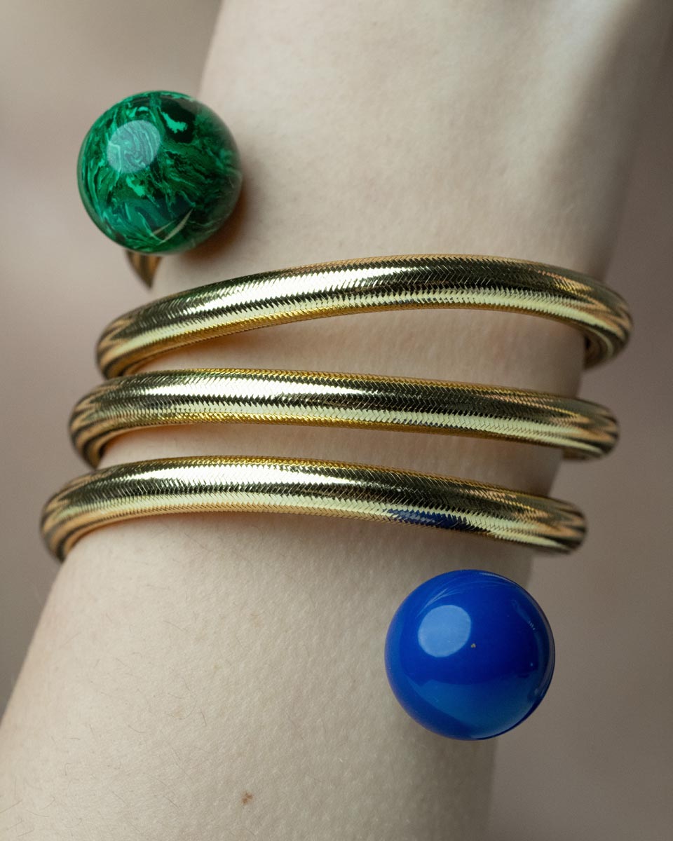 Serpentine Grace, This playful bracelet features a swirling design crafted from bronze, lurex, thermoplastic, and metal, adorned with vibrant lapis lazuli and malachite beads, offering a joyful burst of color that captures the spirit of artistic expression and individuality.