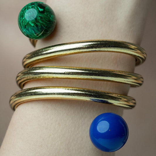 Serpentine Grace, This playful bracelet features a swirling design crafted from bronze, lurex, thermoplastic, and metal, adorned with vibrant lapis lazuli and malachite beads, offering a joyful burst of color that captures the spirit of artistic expression and individuality.