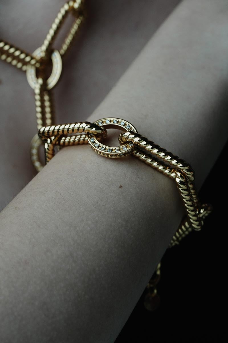 Tidal Chains, Distinctive chain bracelet crafted from brass, featuring striking geometric links and a central circle accent adorned with shimmering zircon stones.