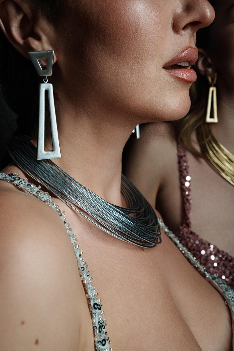 Imperial Strands, A striking silver multi-layered necklace crafted from a blend of bronze, lurex, metal and thermoplastic, offering a modern twist on classic elegance.
Available in gold and silver finishes.