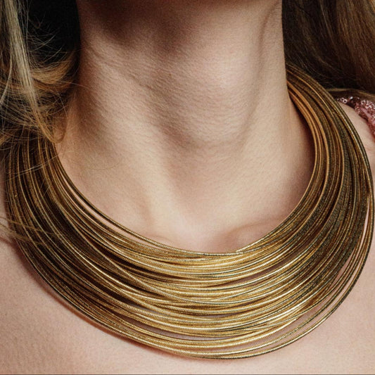 Imperial Strands, A striking silver multi-layered necklace crafted from a blend of bronze, lurex, metal and thermoplastic, offering a modern twist on classic elegance.
Available in gold and silver finishes.
